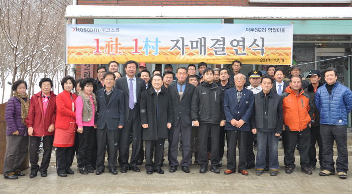 강원도 춘천시 서면 덕두원2리 마을회관에서 코스콤 우주하 사장(앞줄 왼쪽부터 일곱 번째)과 유근선 이장(앞줄 왼쪽부터 여덟 번째)이 마을주민 등 70여 명이 참석한 가운데 자매결연패를 교환 후 도농상생을 위한 지속적 교류 약속 후 기념사진